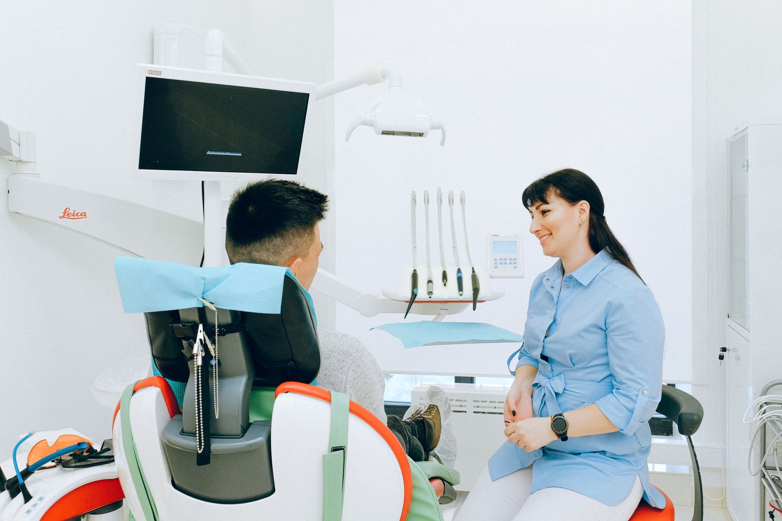 A clinician listening to a patient in the dental chair